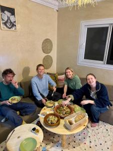 a group of people sitting around a table with food at Surf & bask HOME in Tamraght Ouzdar