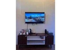 a tv hanging on a wall with a desk at D'BAGOES Luxury Cabin in Sarangan