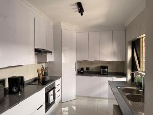 a kitchen with white cabinets and black counter tops at The Kempton Star in Kempton Park