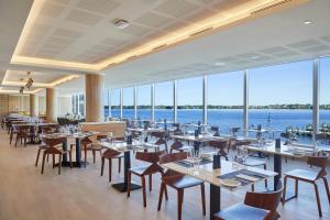 a restaurant with tables and chairs and a view of the water at Doubletree By Hilton Perth Waterfront in Perth
