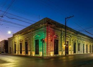 a building with colored lights on the side of a street at La Casa del Centro, Mérida by Cercana in Mérida