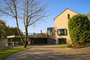 a house with a tree in front of it at Casa Sandra Elisa - Studio aan water in Maasmechelen