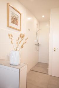 a bathroom with a shower and a vase with flowers on a counter at Landhotel Strandallee in Wunstorf +48 photos