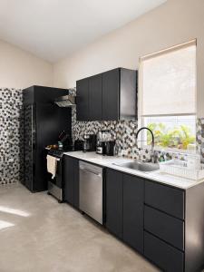 a kitchen with black cabinets and a sink and a window at Casa Frank - Sophiassuites506 in Brasilito