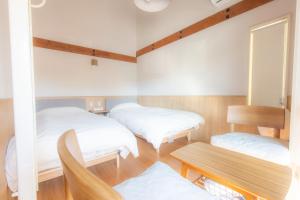 two beds in a room with a table and a bench at 森のオフィス Living in Fujimi