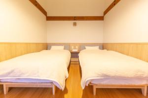 two beds in a room with wooden floors at 森のオフィス Living in Fujimi