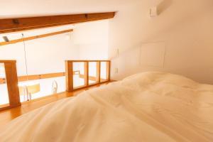 a large white bed in a room with a window at 森のオフィス Living in Fujimi