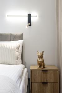 a statue of a cat sitting on a night stand next to a bed at LILY APART - Foodhall & Rooftop Terrace in Gdańsk +117 photos