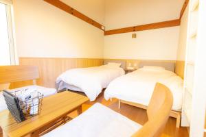 a room with two beds and a wooden table at 森のオフィス Living in Fujimi +30 photos