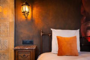 a bed with an orange pillow and a light on a wall at La Suite de Vénus - Chambre à thème Love Room Jacuzzi et Pièce Secrète - Évasion pour deux in Schirrhein