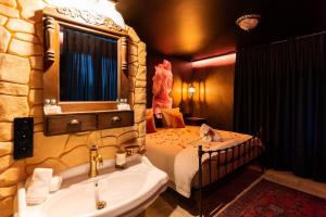 a bathroom with a bed and a sink and a tub at La Suite de Vénus - Chambre à thème Love Room Jacuzzi et Pièce Secrète - Évasion pour deux in Schirrhein