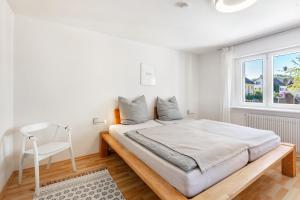 a white bedroom with a large bed and a chair at K8 Living in Wehr