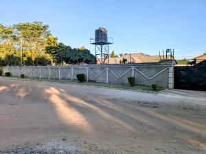 an empty road with a fence and a water tower at Maneya Apartments in Kabwe