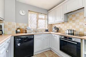a kitchen with white cabinets and a black dishwasher at Rest & Nest in Chelsfield