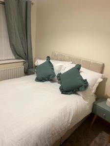 a white bed with two green pillows on it at The Clady Home in Clady +17 photos