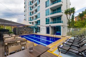 a hotel swimming pool with tables and chairs and a building at The Morgana Poblado Suites Hotel in Medellín