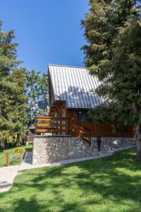 a wooden cabin with a stone wall and trees at Vila Paradiso in Zlatibor