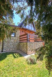 a house with a stone wall and a tree at Vila Paradiso in Zlatibor