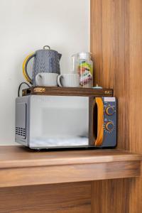 a microwave sitting on top of a wooden shelf at Rest & Nest in Chelsfield +4 photos