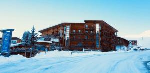 a large building in the snow next to a street at Appartement, 6 pers Casserousse 310 in Chamrousse +2 photos