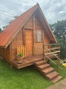 a small wooden cabin with a porch and stairs at Chalé do Carlos in Ibiúna