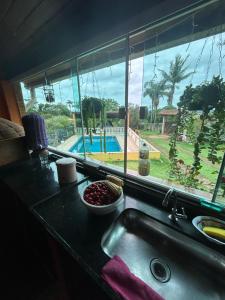 a kitchen sink with a view of a pool through a window at Chalé do Carlos in Ibiúna