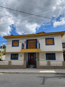 a white house with blue windows on a street at Casa Julieta in Serra Negra