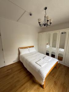 a bedroom with a white bed and a chandelier at Park View in Goodmayes +11 photos