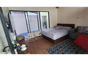 a small bedroom with a bed and a couch at D'BAGOES Luxury Cabin in Sarangan +4 photos