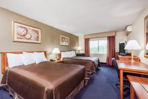 a hotel room with two beds and a desk at Red Carpet Inn Lancaster in Lancaster