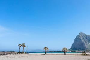 a beach with palm trees and a mountain at Casa Sciura in San Vito lo Capo