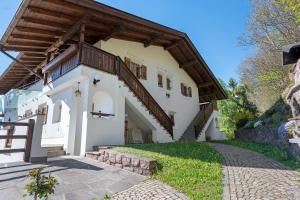 a white house with a wooden roof and stairs at Grafaierhof in Kastelruth