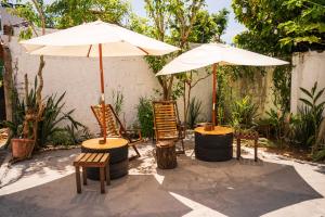 a patio with two chairs and an umbrella at Nossa Casa Itacaré in Itacaré