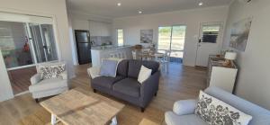 a living room with a couch and chairs and a kitchen at Pelican Lagoon Retreat in Pelican Lagoon