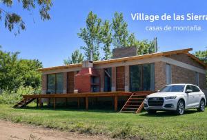 a house with a car parked in front of it at Village De Las Sierras in Sierra de la Ventana