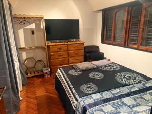 a bedroom with a bed and a dresser with a television at Hostel amplio y confortable in Munro