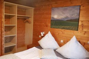 a bedroom with a bed with white pillows and a painting at Ferienhaus Tauber 21 in Hayingen