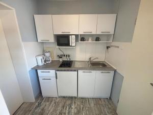 a small kitchen with white cabinets and a sink at Tief 12 Seeigel 31 in Wangerland