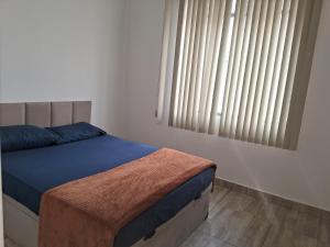 a bedroom with a bed and a window with blinds at Pousada Paula Lima II in Juiz de Fora