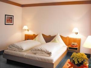 ein Schlafzimmer mit einem Bett mit weißen Laken und Kissen in der Unterkunft Knüllhotel Tann-Eck in Knüllwald + 101 Fotos