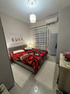 a bedroom with a bed with a red comforter at Gemini Downtown Apartment in Zakynthos