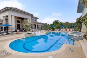 a pool with chairs and umbrellas next to a building at Landing Apartments - Reserve at City Place in Conroe