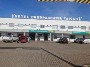 a building with cars parked in a parking lot at Hotel Dom Mineiro in Curvelo