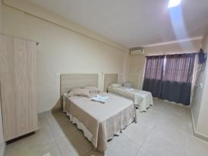 a bedroom with two beds and a window at Hotel Dom Mineiro in Curvelo +15 photos