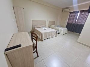 a room with two beds and a table and chairs at Hotel Dom Mineiro in Curvelo