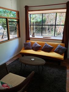 a living room with a couch and two windows at Beautiful cabin on Easter Island in Hanga Roa +1 photo