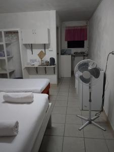 a small room with two beds and a fan at Kathy B Guesthouse in Luganville