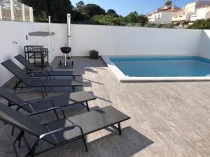 a group of chairs sitting next to a swimming pool at Casa Dulcelina Monte Gordo, Algarve, Portugal in Monte Gordo