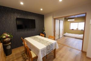 a dining room with a table and a television on a wall at 嵐lan in Kyoto