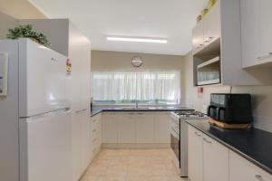 a kitchen with white cabinets and a white refrigerator at Betty's Place in Amity Point